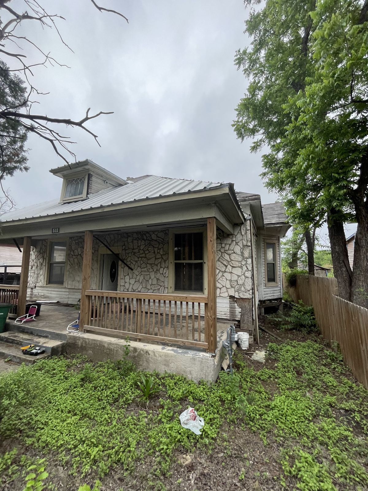 Stone craftsman house before renovation, overgrown yard